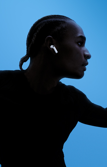 藍色背景前有一個人戴住 AirPods 5 張開雙臂