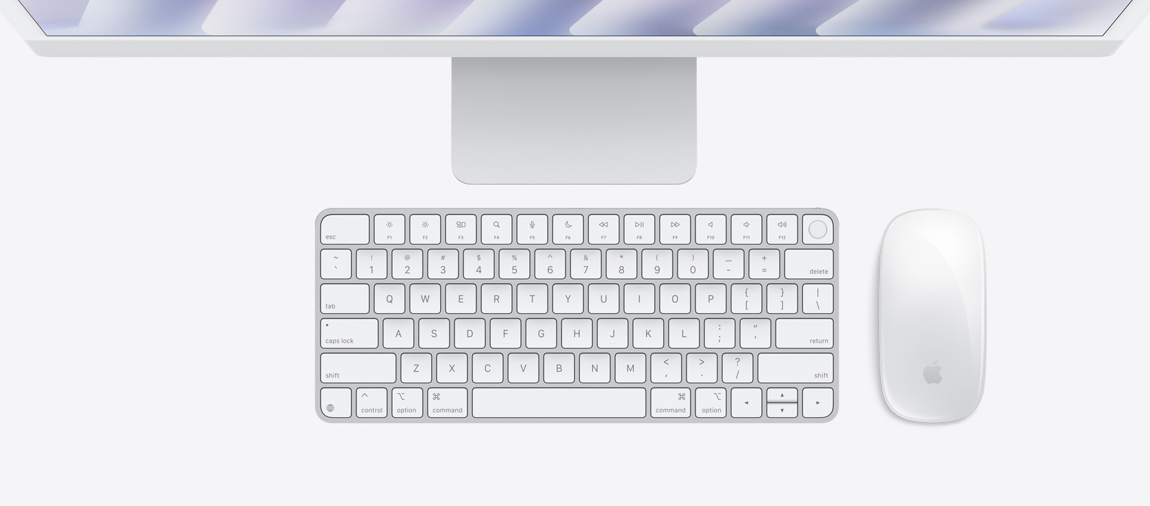 Imagem aérea de um iMac prateado com mouse e keyboard na mesma cor
