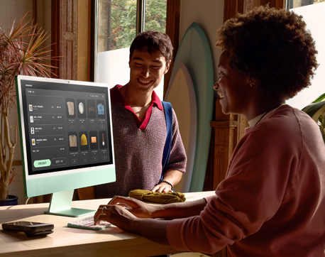 Dos personas en una habitación con mucha luz. Una mujer usando un iMac con pantalla de vidrio nanotexturizado y un hombre de pie, cerca de ella