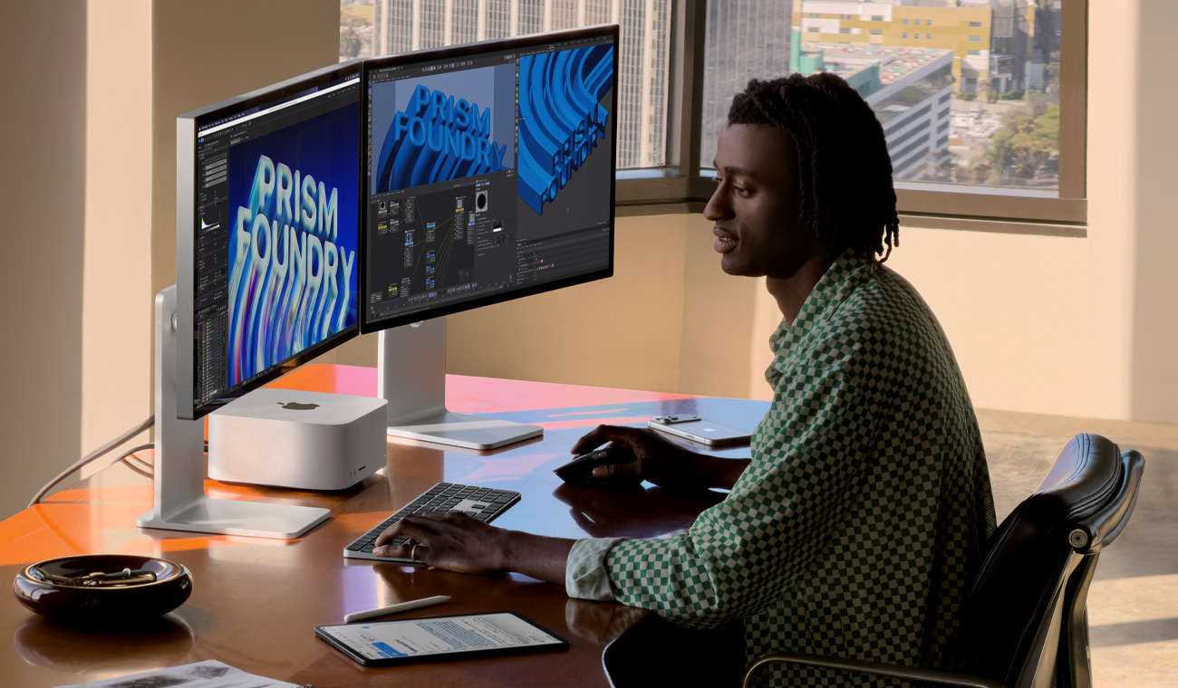 Person sitting at a desk with a Mac Studio centered between two Studio Displays, screens show various projects in-process in animation and editing apps