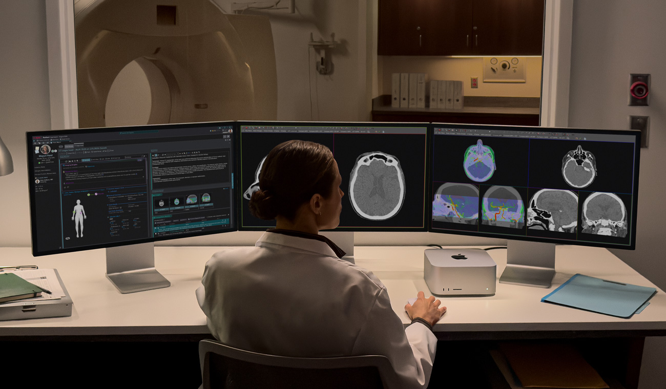 A person is sitting at a desk with three Studio Displays side by side, Mac Studio is on the desk, all screens show medical imaging software applications